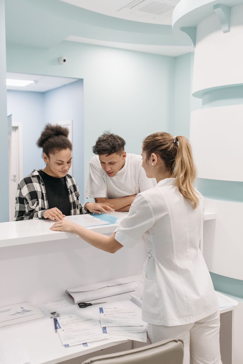 A nurse speaking with a patient at a reception counter