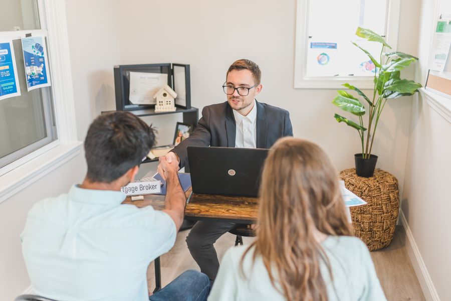 Two clients discussing their mortgage with a broker in a modern office