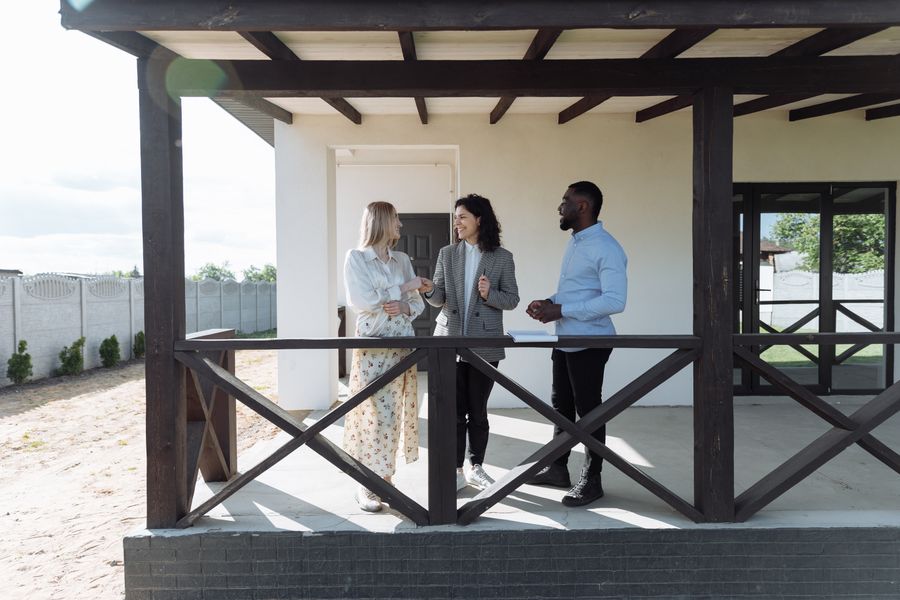 A real estate agent discussing property details with clients on a sunny porch