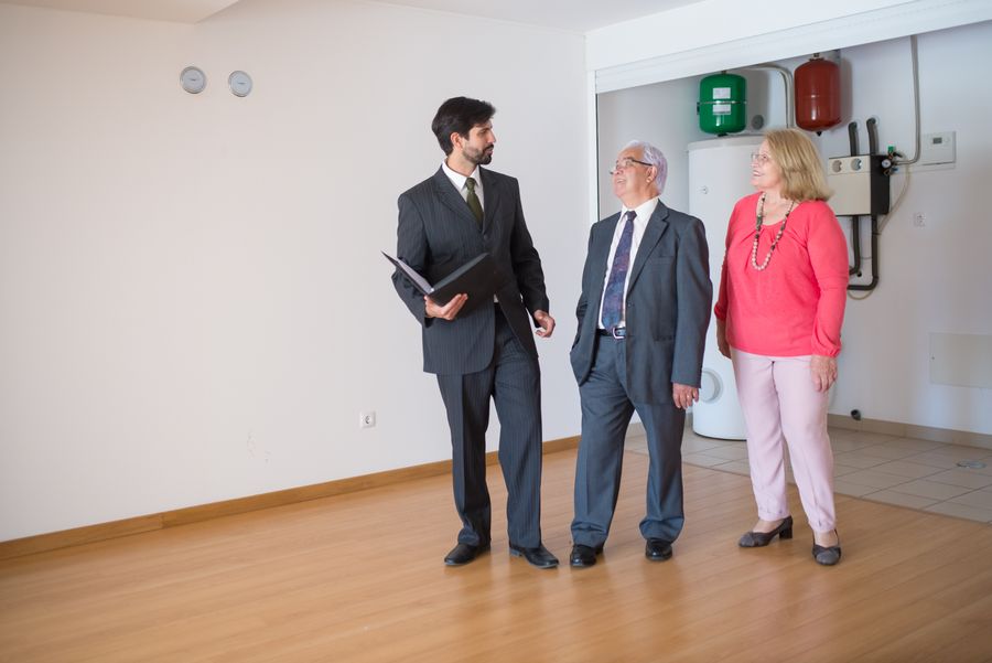 An elderly couple touring a home with a realtor and discussing their real estate options