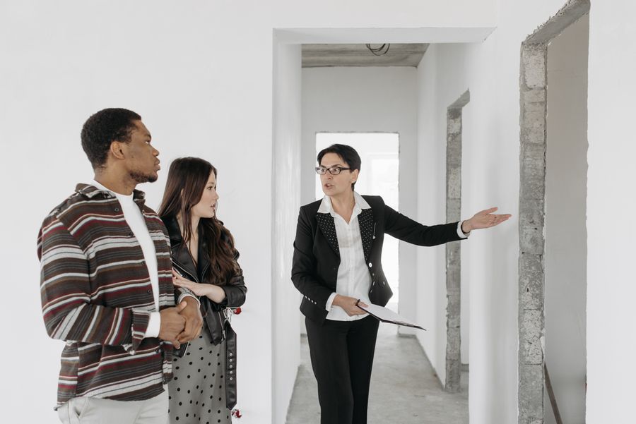 A buyer's agent presents property features to a couple during an apartment viewing