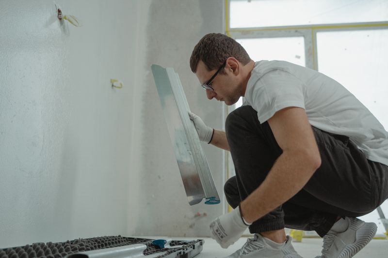 Applying plaster to an interior wall with a metal trowel