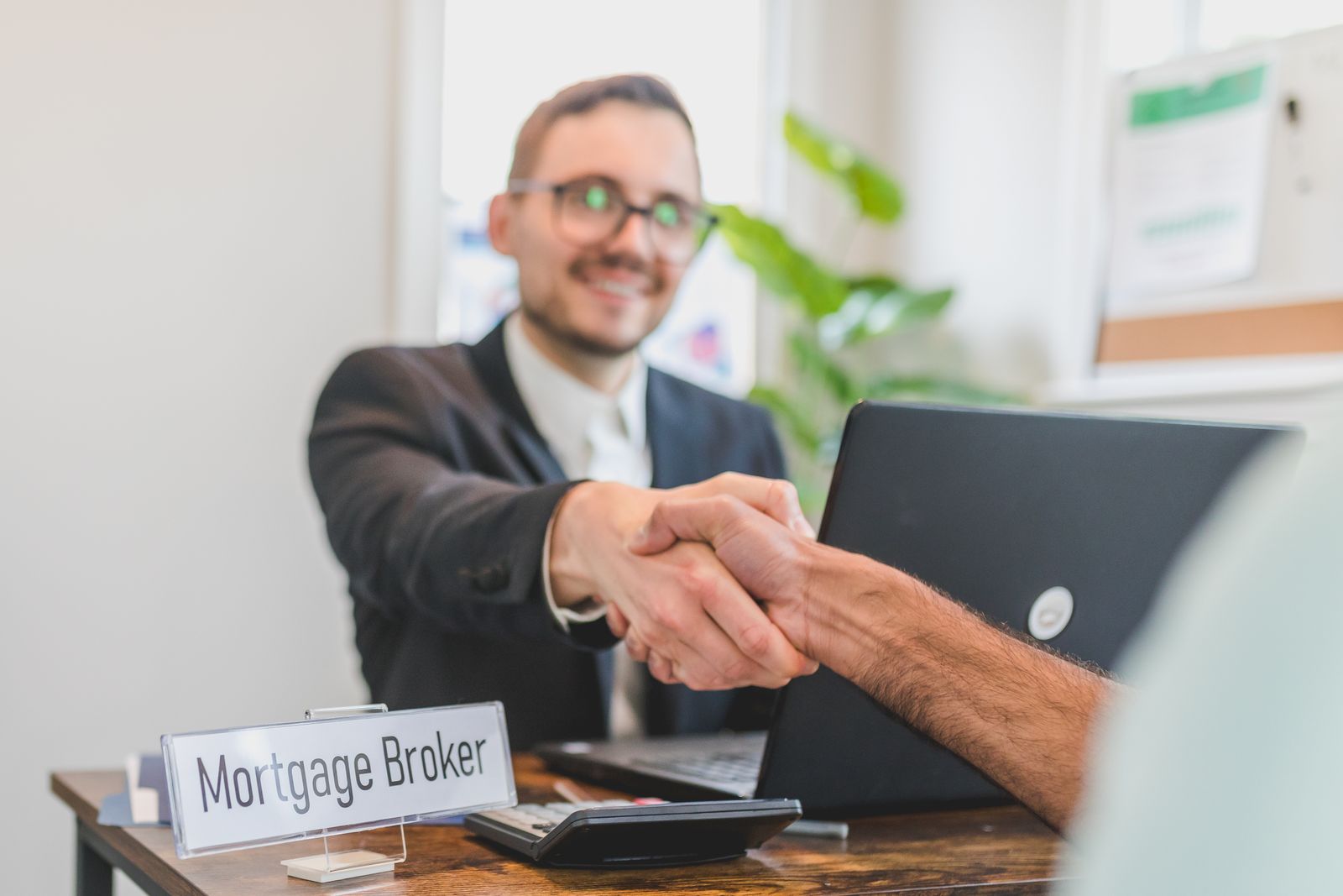 A broker and client shaking hands in a bright, modern office