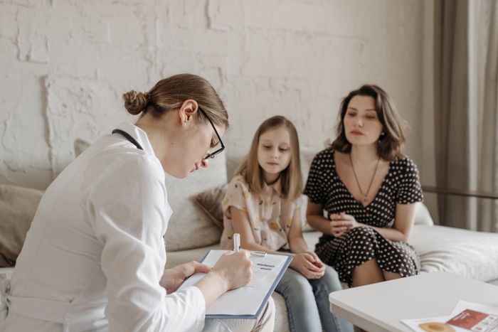 Practitioner taking notes during a consultation with a parent and child