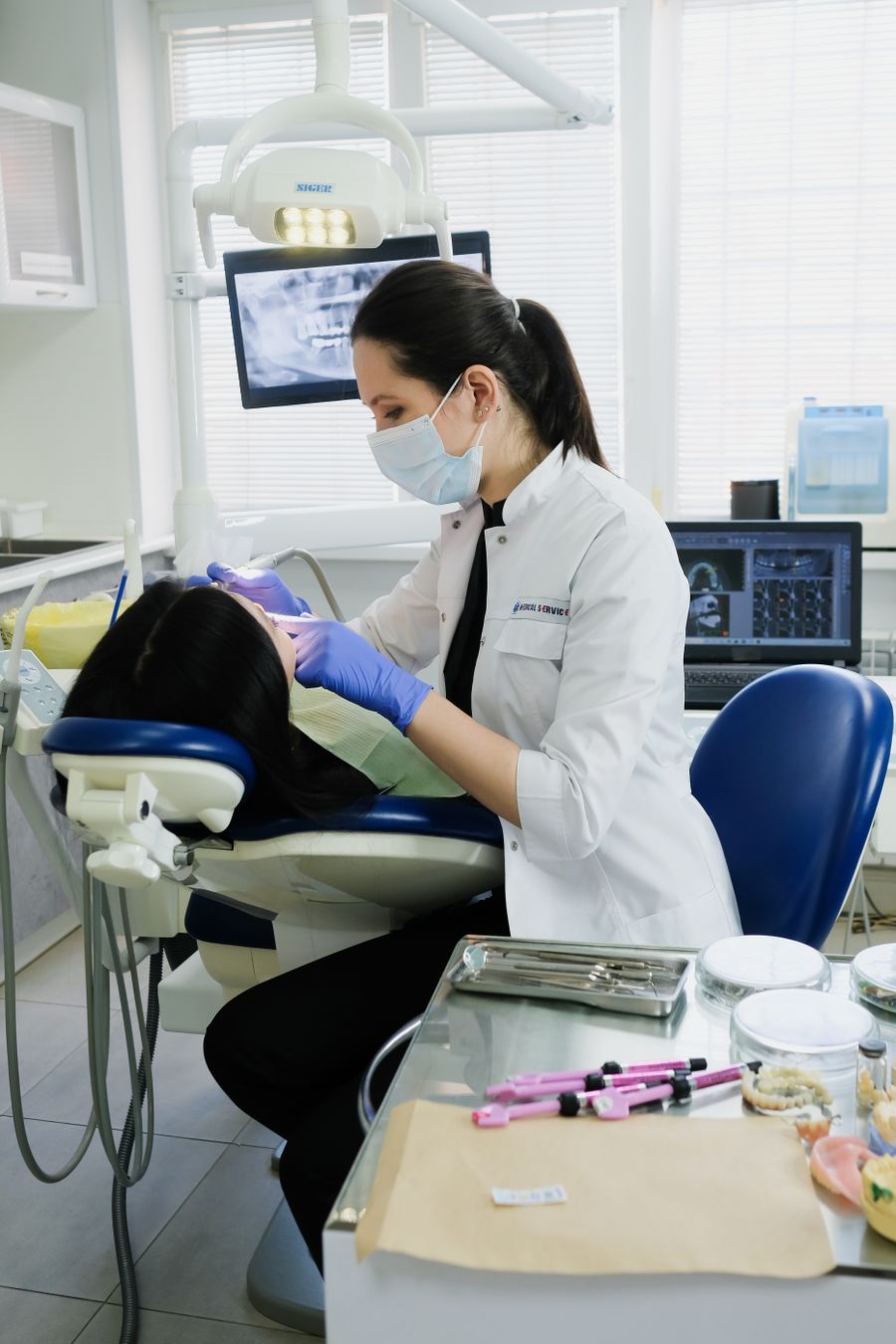 A female dentist cleaning a patient's teeth in a modern dental clinic