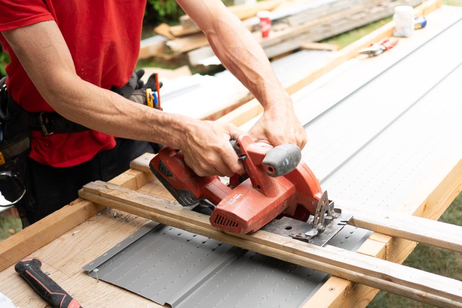 A carpenter cutting a length of timber with a circular saw at an outdoor construction site
