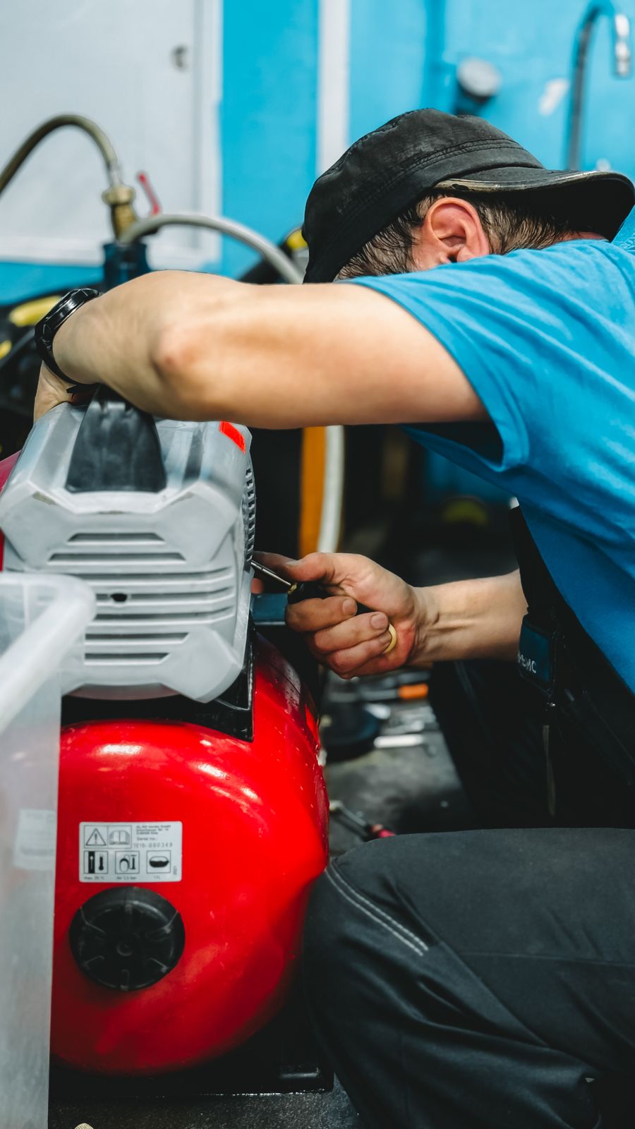 A focused technician repairing an air compressor on a bench in a workshop