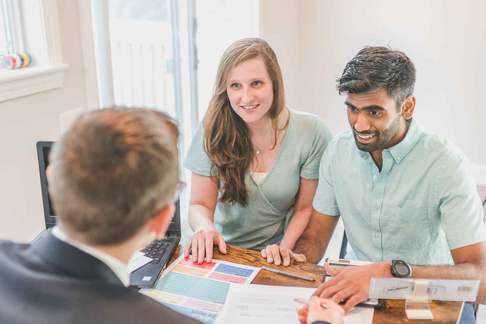 A broker talking a couple through property and loan details at a table indoors