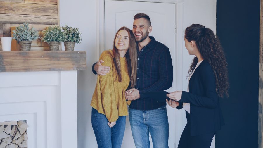 A happy couple sitting in a modern living room discussing a property purchase with their adviser