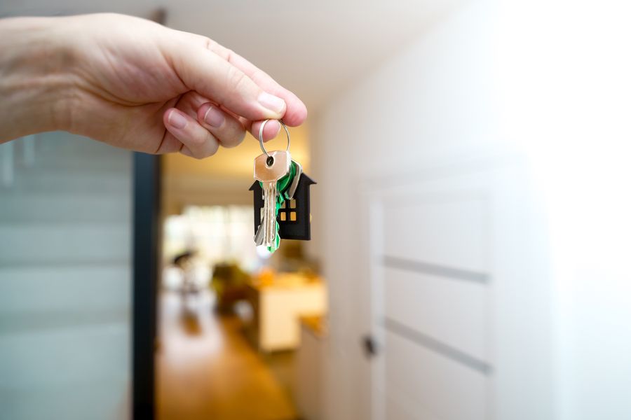 A hand holding house keys inside a modern apartment after settlement