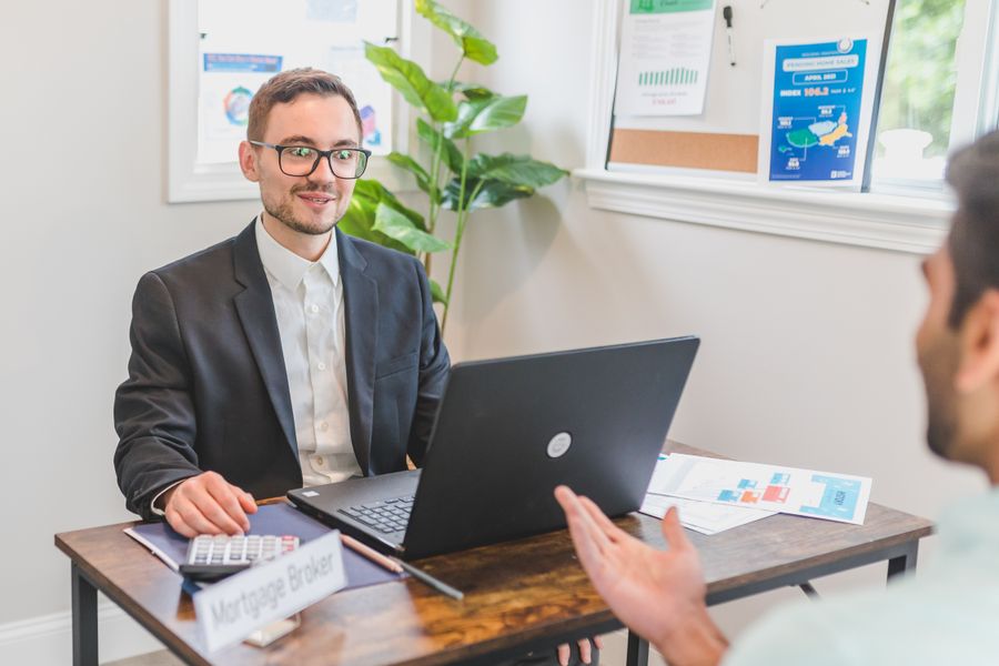 A mortgage broker and client discussing loan options across a desk in a modern office