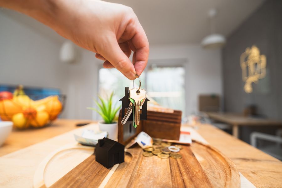 A hand holding keys in a modern living room after a property settlement