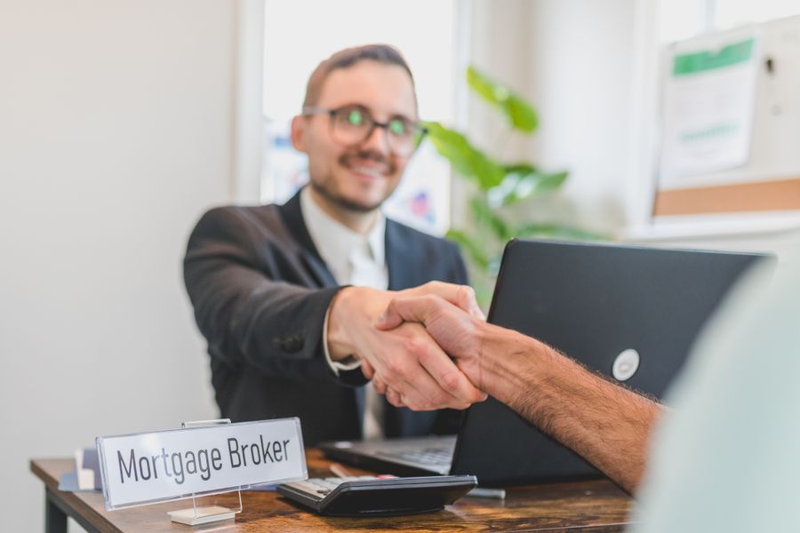 Mortgage broker shaking hands with a client in a bright office