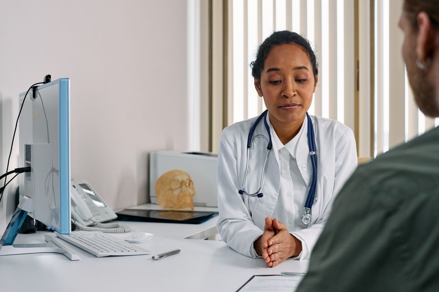 A female doctor in a modern medical office consulting with a patient across a desk