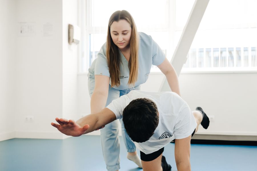 A physiotherapist assisting a patient through a stretching exercise indoors