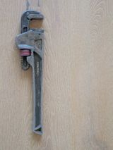 A pipe wrench hanging on a timber wall
