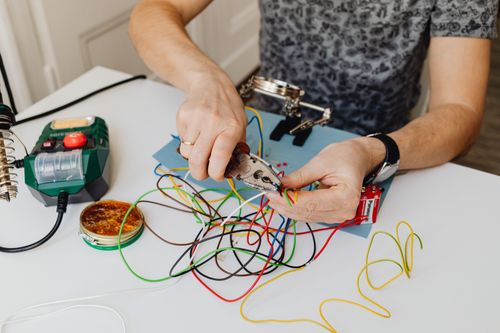 Close-up of hands working with colourful wires at a workbench