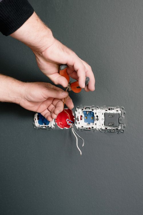 Close-up of hands wiring a wall power point with a screwdriver