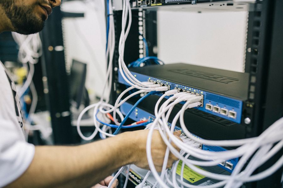 A technician connecting Ethernet cables into a network rack