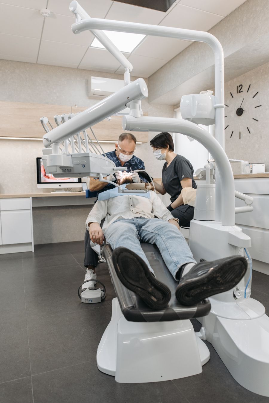 A dentist and assistant examining a patient together in a modern dental clinic