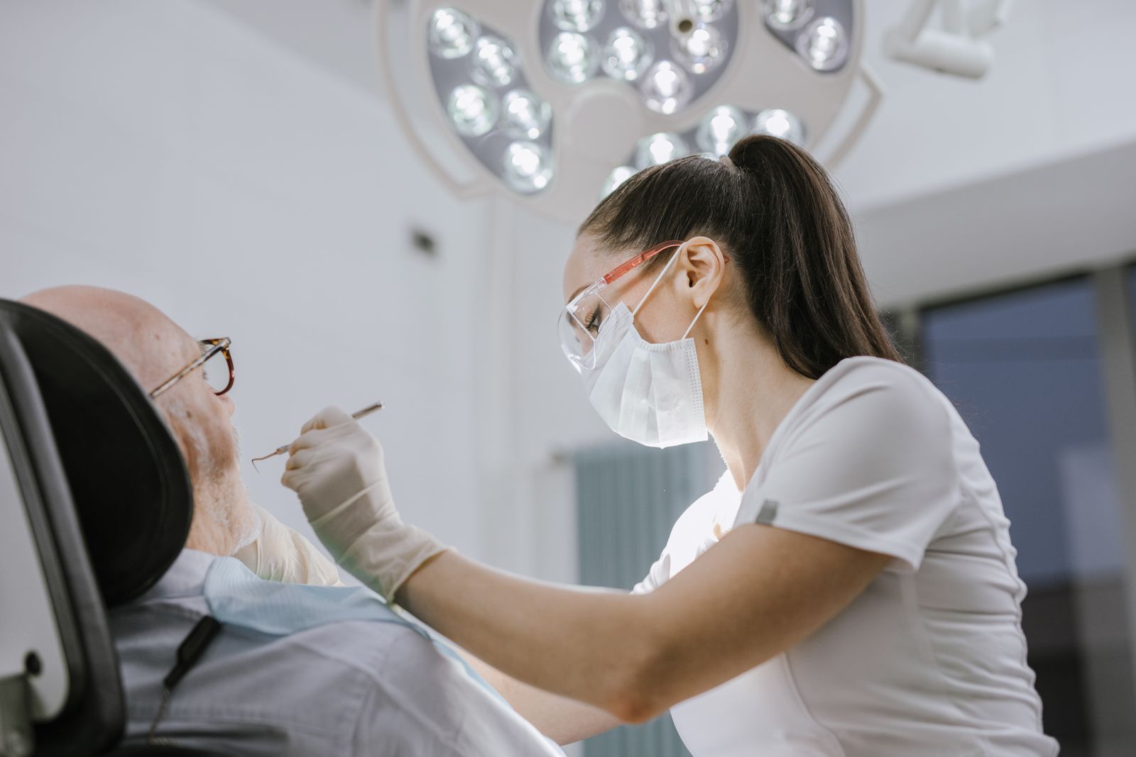 A dentist working carefully on a patient in a brightly lit surgery