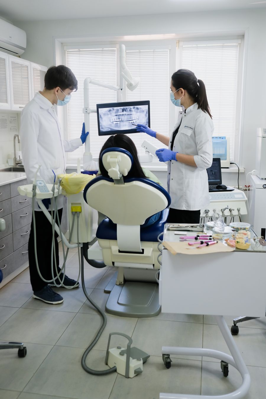 A dental team examining a patient with modern equipment in a bright clinic