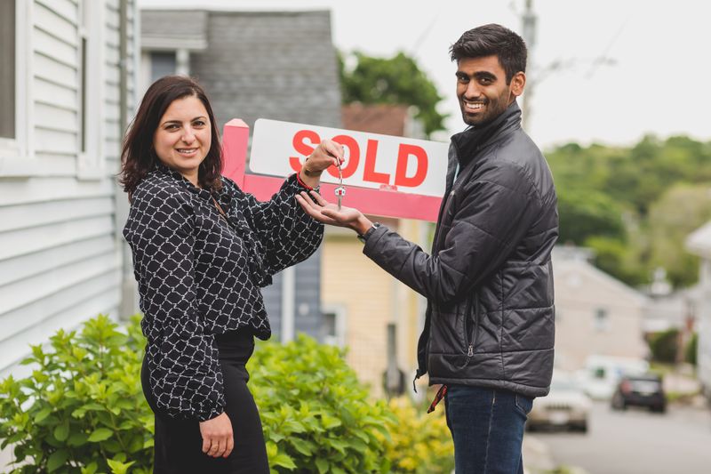 A sold sign outside a house as keys change hands
