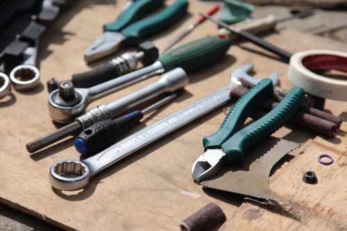 Close-up of hand tools including pliers and a wrench laid out on a wooden board