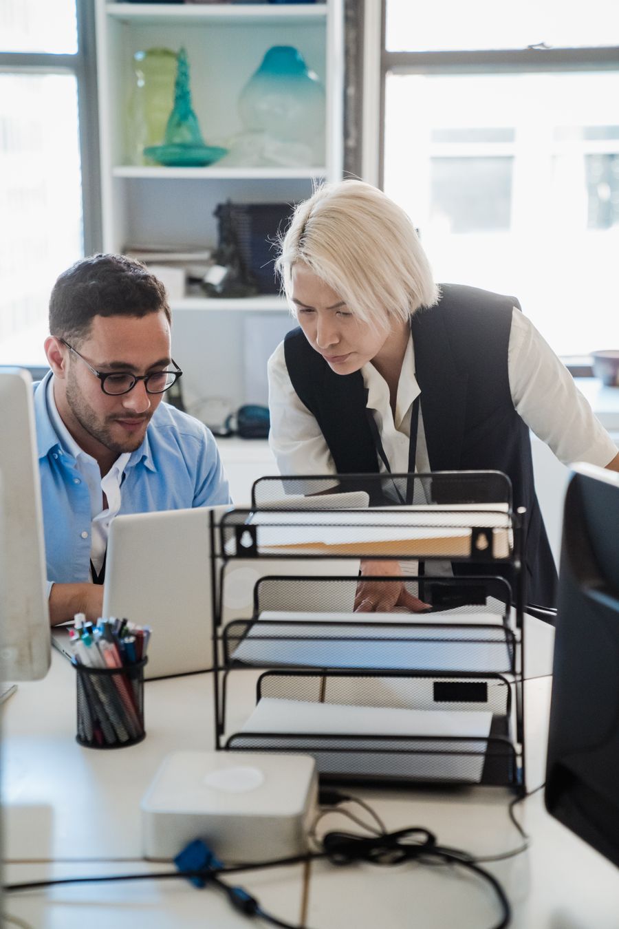 Two IT support colleagues troubleshooting an issue together at a desktop monitor