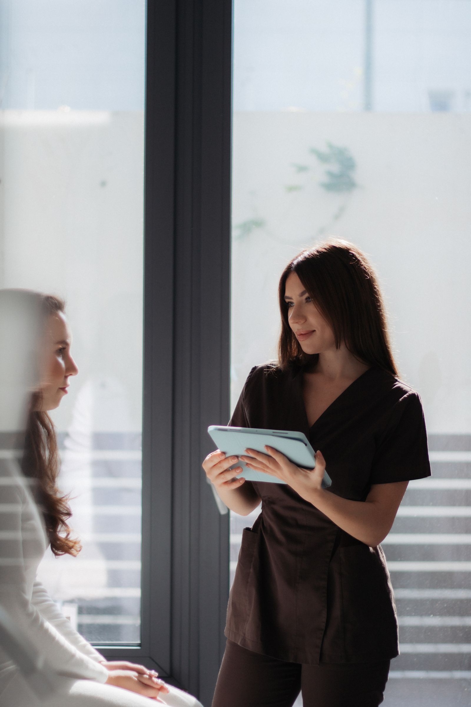 A clinician reviewing a care plan on a tablet with a patient in a well-lit clinic